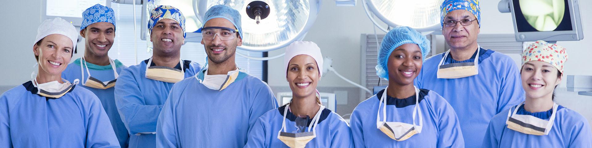 Group of people in operating room wearing scrubs smiling